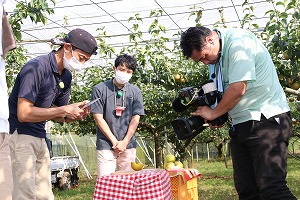 日本テレビの取材を受ける鈴木明道さん(左)とリポーターの渡辺裕太さん(中央)